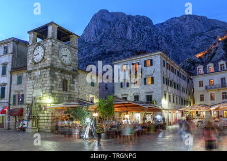 Scène dans la cité médiévale de Kotor, Monténégro, au crépuscule, avec le carré de bras et la tour de l'horloge près de la porte d'entrée maritime. Banque D'Images