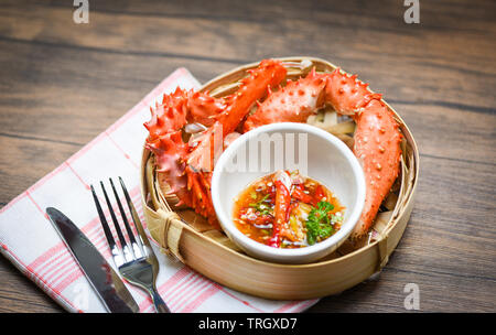 Pinces de crabe bouilli cuit à vapeur en bambou avec le crabe royal d'Alaska et sauce aux fruits de mer sur table à manger contexte / crabe rouge Hokkaido Banque D'Images