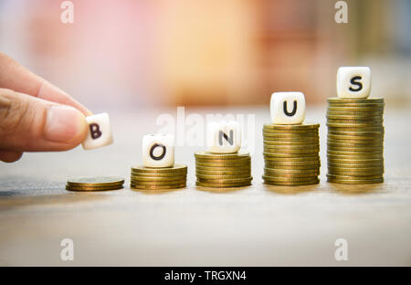 Prime annuelle concept / hand holding paroles de bonus sur pièces pile escalier pour l'encouragement moral sur la table bureaux entreprise Banque D'Images