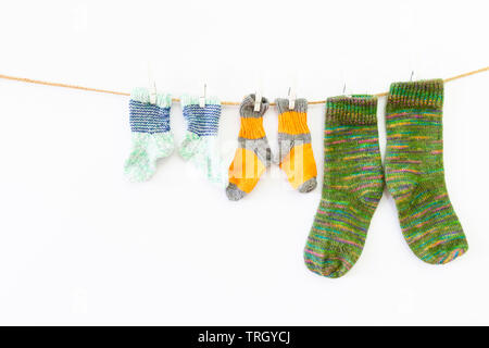 Plusieurs paires de chaussettes de laine colorés de différentes tailles, suspendu à une corde avec fond blanc Banque D'Images