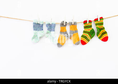 Plusieurs paires de chaussettes de laine colorés de différentes tailles, suspendu à une corde avec fond blanc Banque D'Images