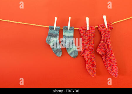 Plusieurs paires de chaussettes de laine colorés de différentes tailles, suspendu à une corde avec fond blanc Banque D'Images