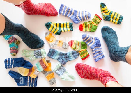 Vue de dessus d'un assortiment de chaussettes de laine de différentes tailles sur fond blanc avec deux paires de pieds portant une chaussette rouge et bleu Banque D'Images