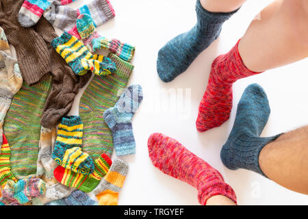 Vue de dessus d'un assortiment de chaussettes de laine de différentes tailles sur fond blanc avec deux paires de pieds portant une chaussette rouge et bleu Banque D'Images