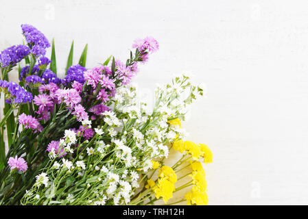 Frais Bouquet coloré de fleurs de printemps jaune avec maman , marguerite Mauve et blanc fleurs de coupe sur fond de bois blanc Banque D'Images