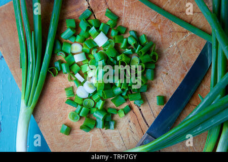 Oignons verts, également connu sous le nom d'oignons verts, oignons de printemps, ou des oignons salade rustique sur planche à découper Banque D'Images