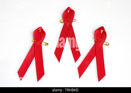 Rubans rouges avec les broches d'or pour le sida concept isolated on white Banque D'Images