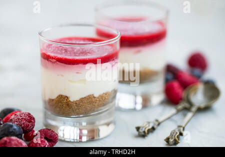 Desserts gâteau au fromage dans les verres, petits fruits rouges frais topping gelly, fromage à la crème et les desserts biscuits digestifs en verres transparents Banque D'Images