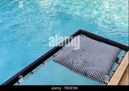 Siège mesh de relaxation avec des oreillers sortir sur piscine Banque D'Images