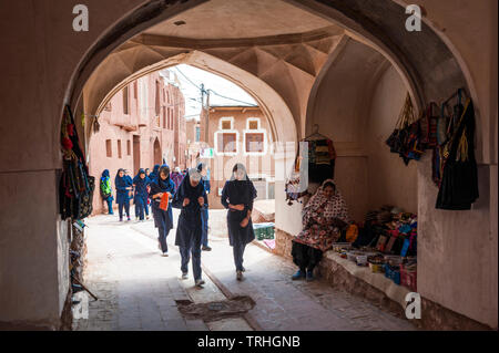 Un groupe de filles marchant à travers une arche dans la vieille ville de Abyaneh, Iran. La ville est une attraction touristique populaire. Banque D'Images