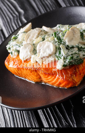 Florentine de saumon est faite avec juteuse, tendre, saumon au four et garni d'épinards et champignons close up sur la plaque sur la table verticale. Banque D'Images