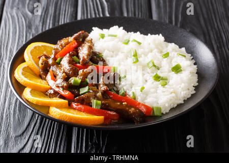 Style asiatique avec boeuf poivron dans une sauce aigre-douce servis avec du riz sur une plaque horizontale sur la table. Banque D'Images