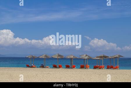 Chaises longues et parasols de paille sur l'une des nombreuses plages de sable à Halkidiki, Grèce Banque D'Images