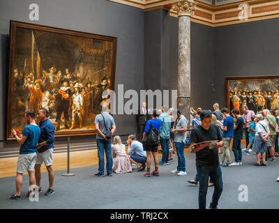 Les touristes à la recherche à la Ronde de nuit, une peinture de Rembrandt Harmenszoon van Rijn, au Rijksmuseum à Amsterdam, aux Pays-Bas. Rembrandt est consi Banque D'Images