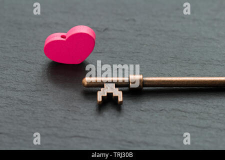 Cadenas en forme de coeur avec clé sur un fond noir en ardoise . La clé du concept du coeur Banque D'Images