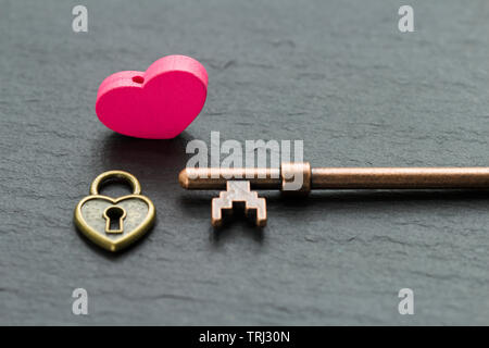 Cadenas en forme de coeur avec clé sur un fond noir en ardoise . La clé du concept du coeur Banque D'Images