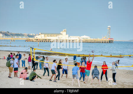 Volley-ball sur la plage de Bournemouth avec la jetée à l'arrière. Le Dorset. Angleterre, Royaume-Uni. Banque D'Images