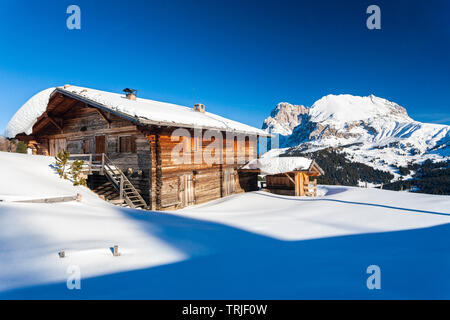 Coucher de soleil sur le Sassolungo et Sassopiatto cabane de bois recouvert de neige, à l'Alpe di Siusi / Seiser Alm, Dolomites, Tyrol du Sud, Italie Banque D'Images