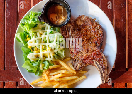 Côtes de porc grillé steak bien-fait avec frites et légumes sur plaque blanche Banque D'Images