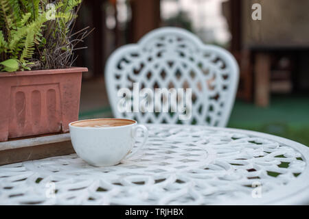 Hot café latte avec forme de fleurs en coupe blanc sur table rétro avec des Banque D'Images