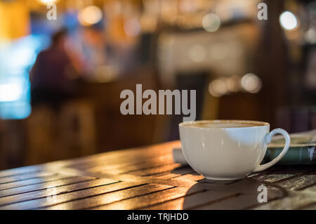 Tasse à café Latte chaud sur table en bois et un bokeh arrière-plan flou Banque D'Images