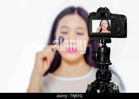 Se concentrer sur l'affichage en temps réel sur l'appareil photo sur un trépied, une adolescente l'utilisation de cosmétiques d'image sur l'écran arrière scène floue avec en arrière-plan. Livestrea vlogger chez les adolescentes Banque D'Images