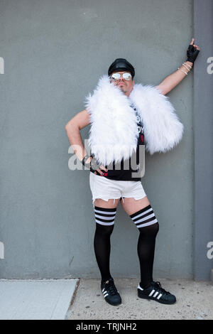 Posée portrait d'un homme vêtu d'un boa blanc et plus les chaussettes au Queens Pride Parade à Jackson Heights, Queens, New York. Banque D'Images