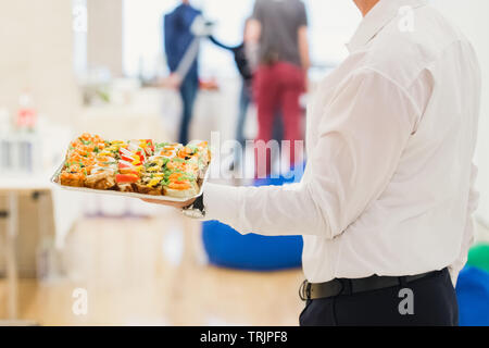 Waiter carrying plaques avec plat de viande sur certains événement festif, fête ou réception de mariage. Banque D'Images