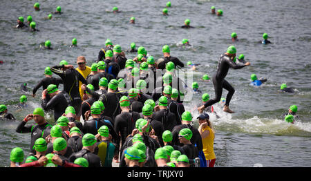 Les triathlètes sauter dans un lac sur le 1er niveau natation section triathlon à un événement tenu à Blenheim Palace, Oxfordshire, UK Banque D'Images