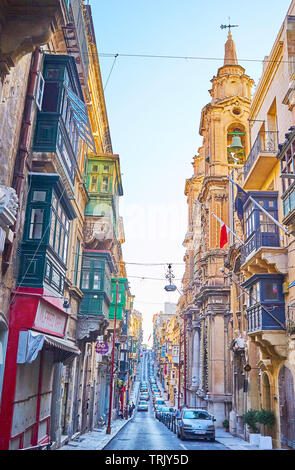 La Valette, MALTE - 19 juin 2018 : Promenade le long de la longue et étroite rue St Paul, bordée de vieux immeubles d'habitation, de petits magasins et cafés de la famille, o Banque D'Images