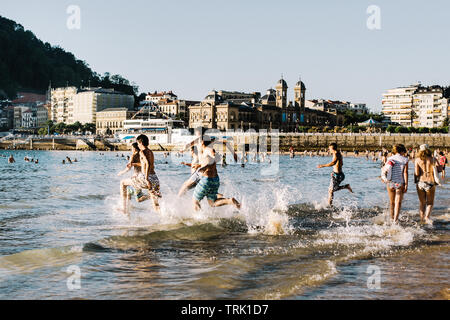 Les personnes bénéficiant de Playa de La Concha beach au coucher du soleil sur une chaude journée d'été à San Sebastian, Espagne Banque D'Images