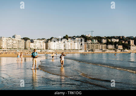 Les personnes bénéficiant de Playa de La Concha beach au coucher du soleil sur une chaude journée d'été à San Sebastian, Espagne Banque D'Images