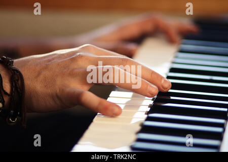 Mains, dont l'une porte un bracelet, jouer une mélodie sur un clavier instrument de musique Banque D'Images