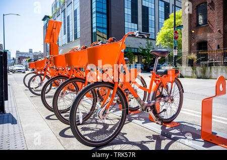 Transport public rue orange louer des vélos avec panier pour voyager autour de la ville en ligne sur support réseau de location de stationnement en attente de cyc Banque D'Images