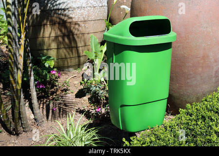 Poubelle verte photographié au cours d'une journée ensoleillée dans un jardin à Madère, au Portugal. Dans cette photo il y a le bac de recyclage et quelques plantes vertes. Banque D'Images