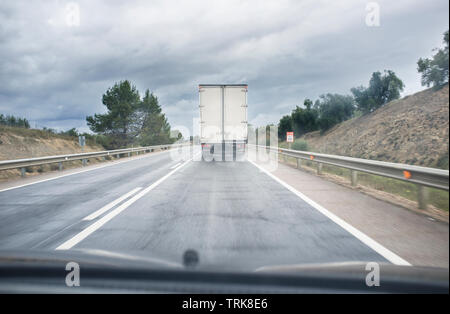 Derrière la conduite de camion lent sur la route un jour de pluie. Vue depuis l'intérieur de la voiture Banque D'Images