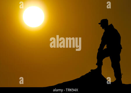 Silhouette de soldat au fusil contre un coucher de soleil Banque D'Images