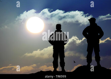 Silhouette de soldat au fusil contre un coucher de soleil Banque D'Images