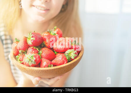 Plaque en bois avec des fraises en fille Main sur fond clair, concept d'aliments biologiques Banque D'Images