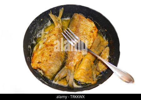 La photo de l'ensemble du poisson frit sans tête sur le gril ou la poêle avec une fourchette sur elle Banque D'Images