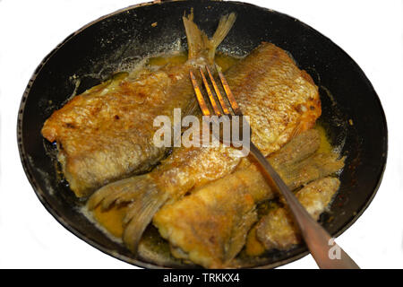 La photo de l'ensemble du poisson frit sans tête sur le gril ou la poêle avec une fourchette sur elle Banque D'Images