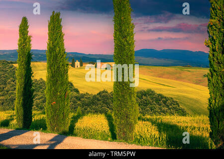 Incroyable coucher du soleil coloré, pittoresque Vitaleta chapelle (Capella di Vitaleta) avec les champs de céréales au coucher du soleil sur la colline, près de Pienza, Toscane, Italie, Europ Banque D'Images