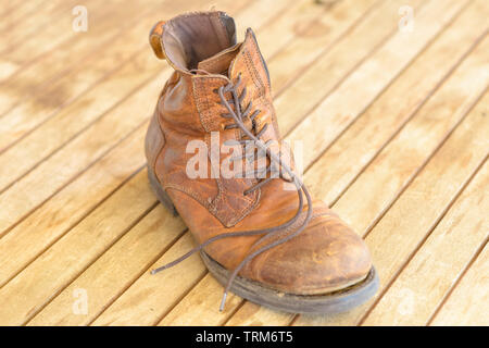 Seul old brown randonnées bien usé de boot avec lacets en cuir et d'usure sur un sol en bois (vue de dessus Banque D'Images