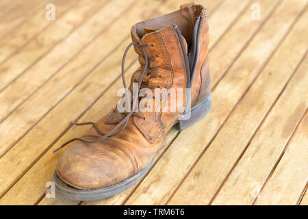 Seul old brown randonnées bien usé de boot avec lacets en cuir et d'usure sur un sol en bois (vue de dessus Banque D'Images