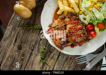 Escalope de porc avec la sauce dans une assiette blanche sur une table en bois Banque D'Images