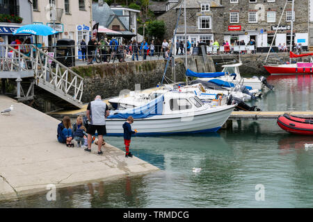 Padstow, Cornwall, England UK : une famille la pêche de crabes sur la cale avec le port et les bateaux derrière. Banque D'Images