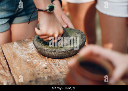 Femme moud de l'herbe avec un pilon dans un mortier Banque D'Images