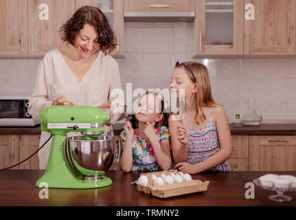 Grande famille - une mère et ses trois enfants - deux filles et un fils, cuisinier dans la cuisine, fouetter la crème dans un blender. Focus sélectif. Banque D'Images