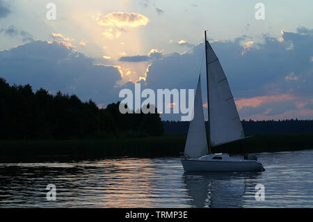 Bateau à voile contre le coucher de soleil sur le lac d'Augustow. Segelboot gegen die auf dem Augustów-See untergehende sonne. J'Żaglówka zachodzące słońce. Banque D'Images