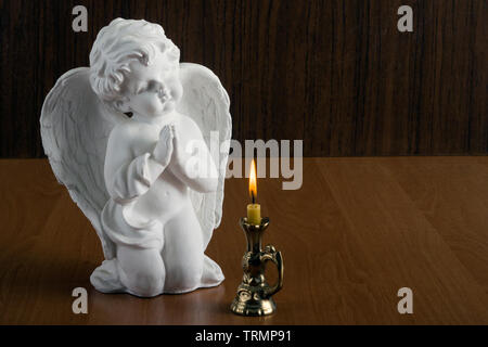 Angel. Guardian Angel croisa ses mains en prière. Fond de bois. Vue de côté et de près. Banque D'Images